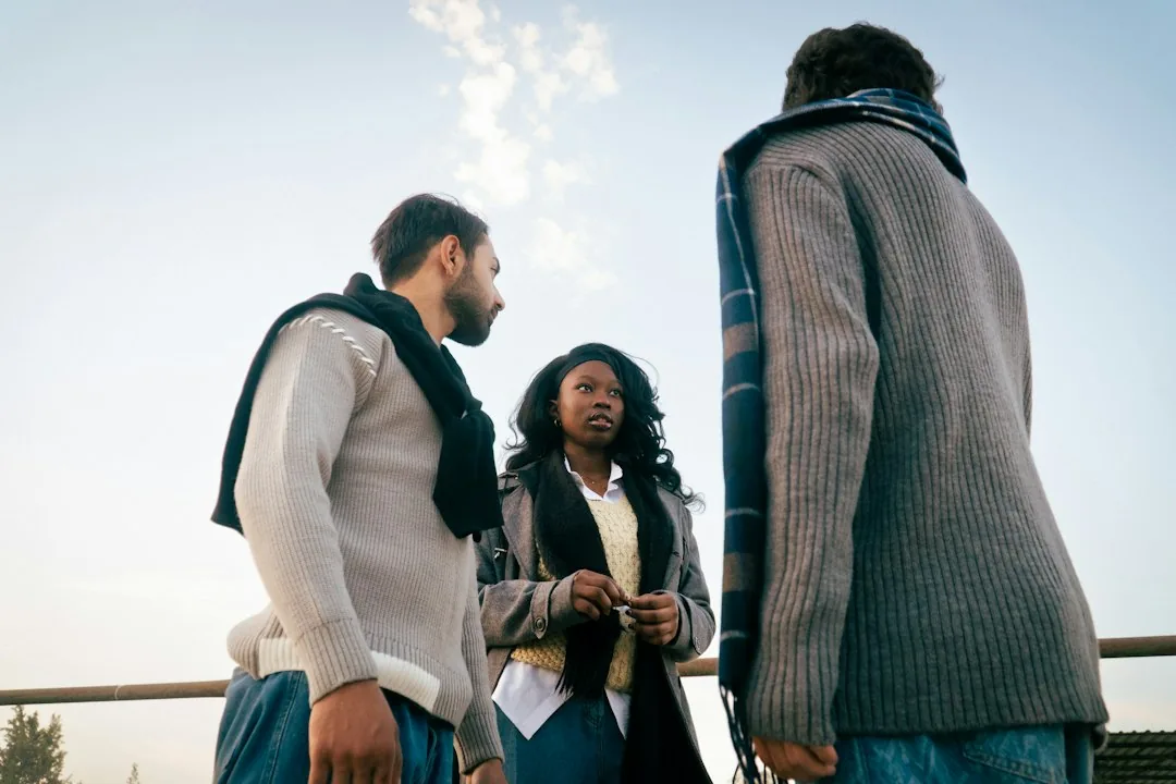 Trois personnes échangent à l’extérieur.